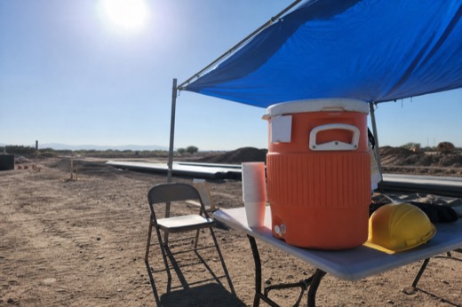 Crew water cooler and shade setup on a hot job site